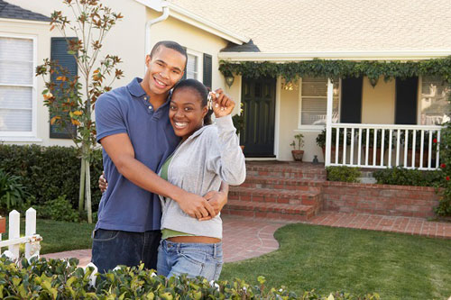 photo of young couple holding keys to new house