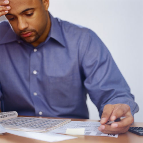 photo of man looking at documents with head laying in hand