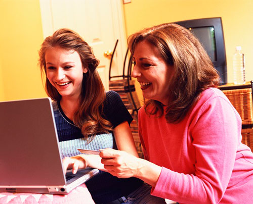 photo of a young girl and her mom in on laptop computer smiling