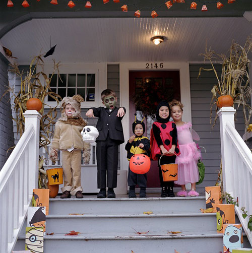 photo of children in halloween costume in front of house