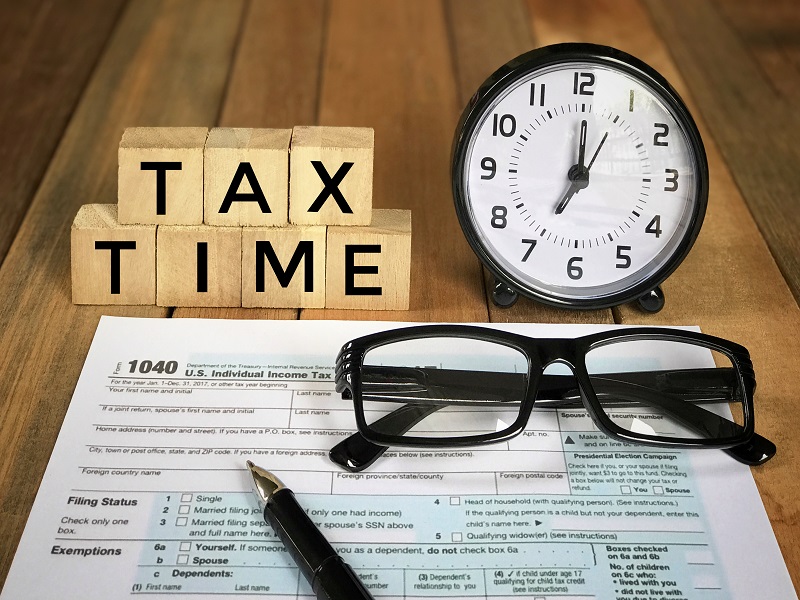 Picture that Says Tax Time with clock, glasses and taxform