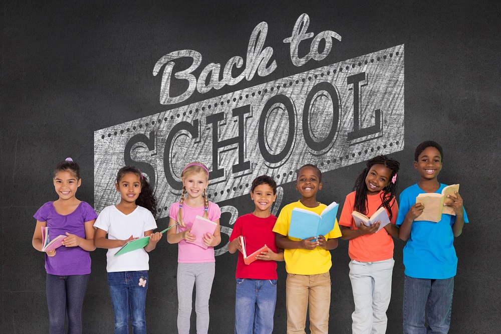 picture of kids with school supplies in front of back to school written on chalk board